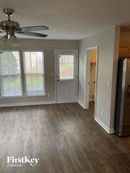 an empty living room with wood floors and a ceiling fan
