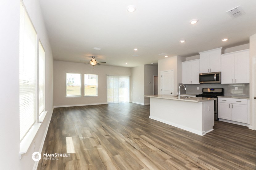 an open kitchen and living room with white cabinets and wood flooring