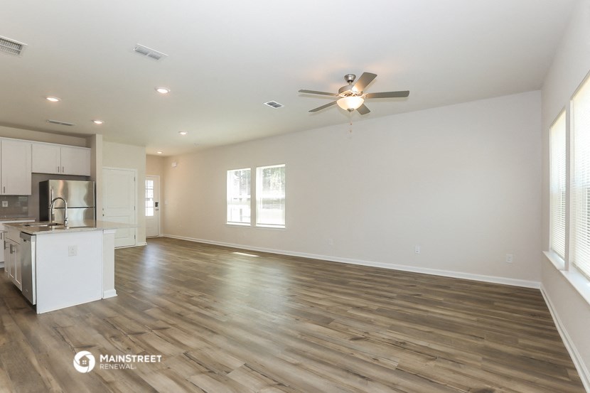 the living room and kitchen of a new home with a ceiling fan