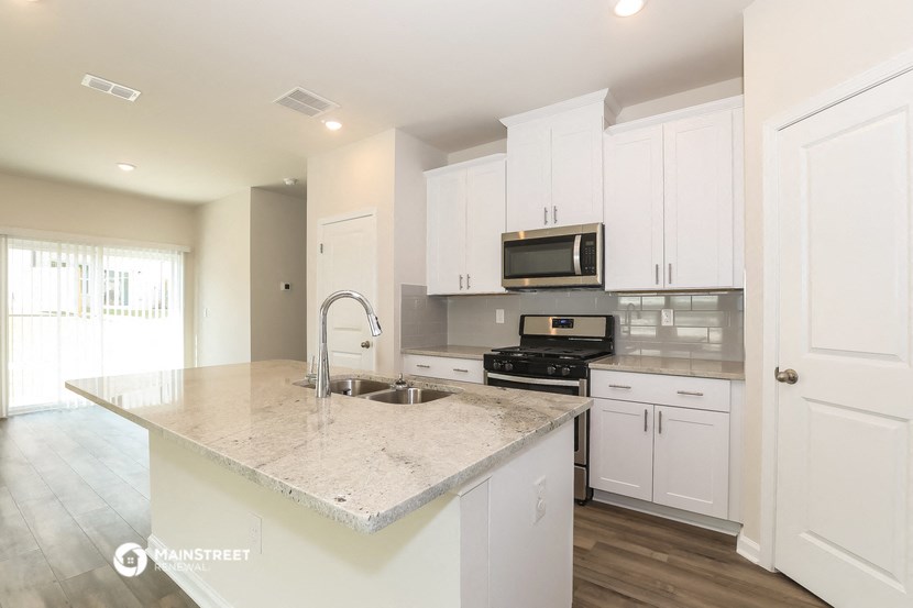 a kitchen with white cabinets and a marble counter top