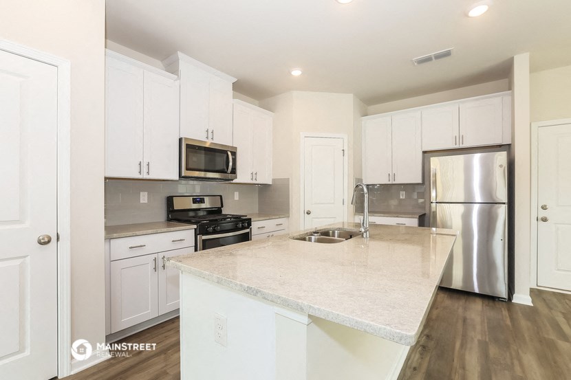 a large kitchen with white cabinets and stainless steel appliances