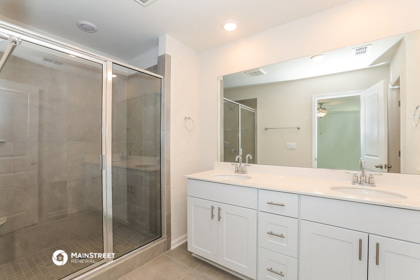 a bathroom with white cabinets and a shower and a sink