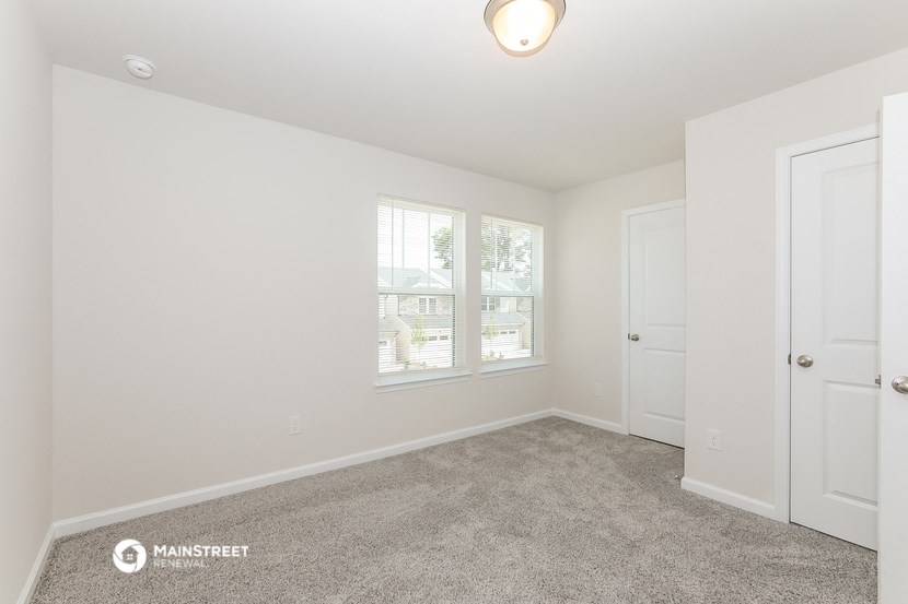a bedroom with carpet and white walls and a door and window
