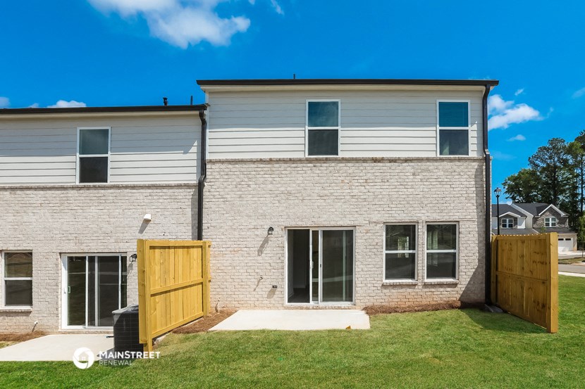 a white brick house with a wooden gate and a yard