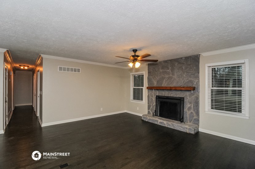 a living room with a fireplace and a ceiling fan