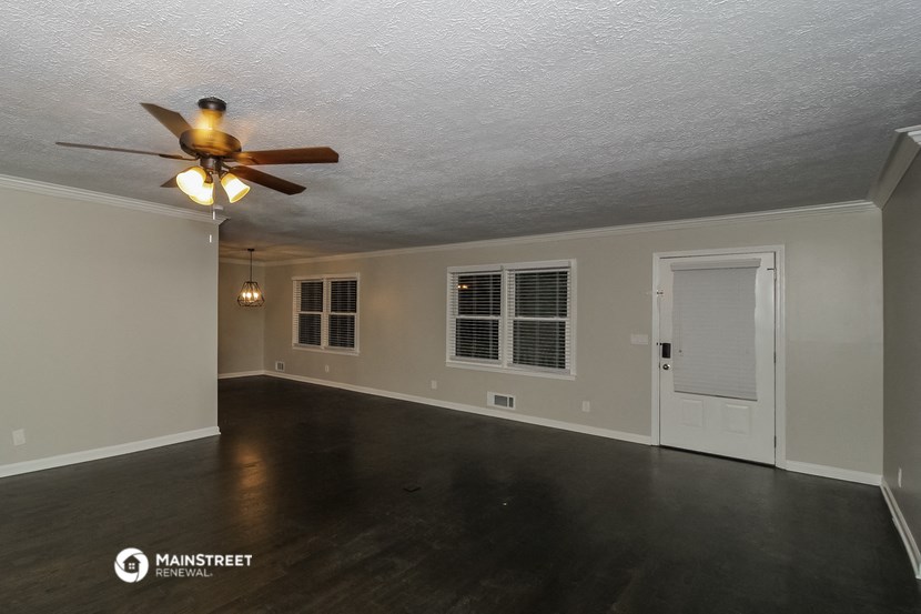 the living room of an empty house with a ceiling fan