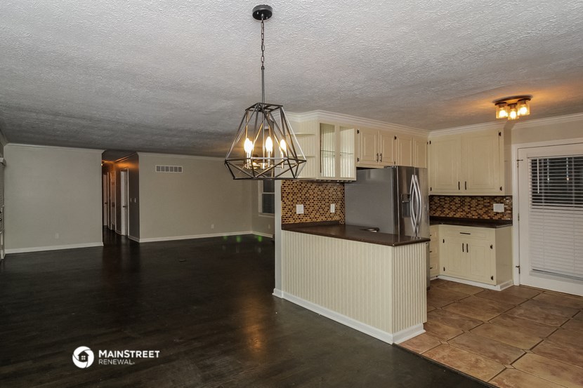 a kitchen and living room with a large island and a chandelier