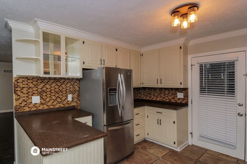 a kitchen with white cabinets and a stainless steel refrigerator