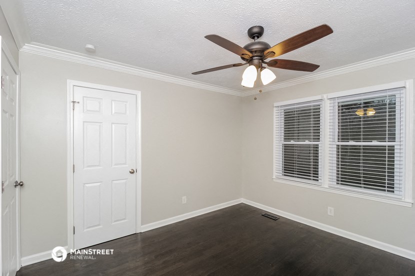 the living room of a house with a ceiling fan and a window