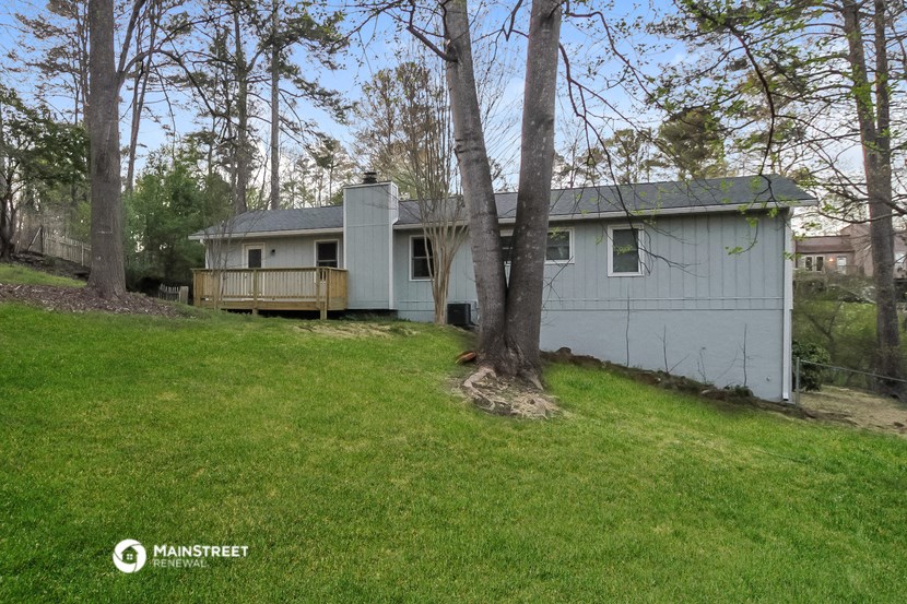 a small white house with a yard and trees