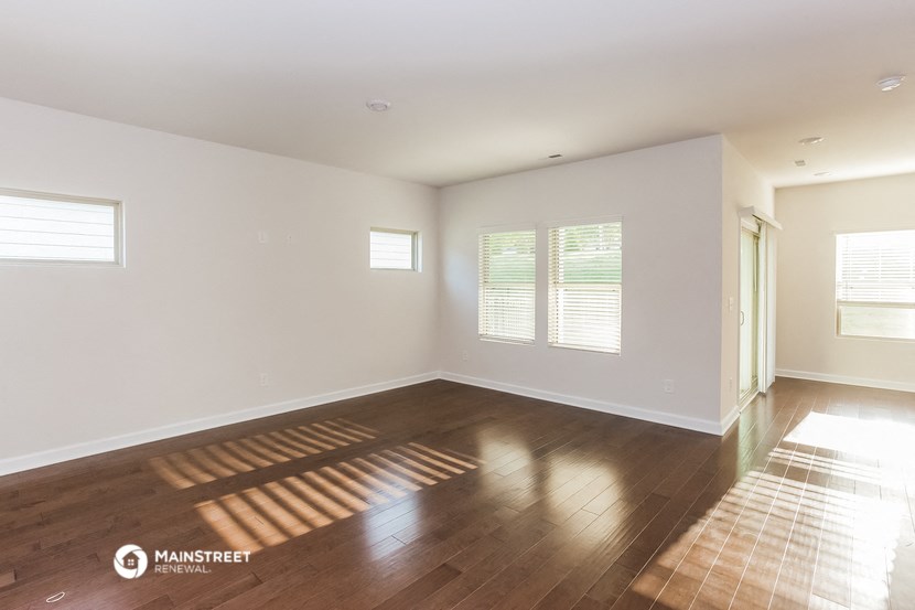 an empty living room with wood floors and white walls