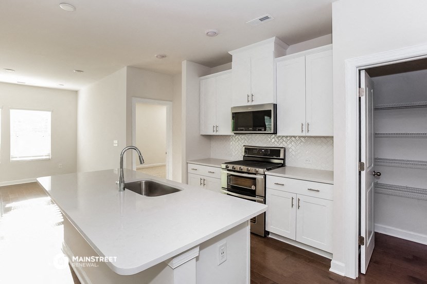 a white kitchen with stainless steel appliances and white counter tops