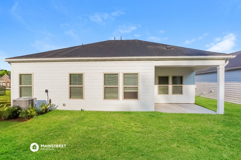 the backyard of a white house with a lawn and a driveway