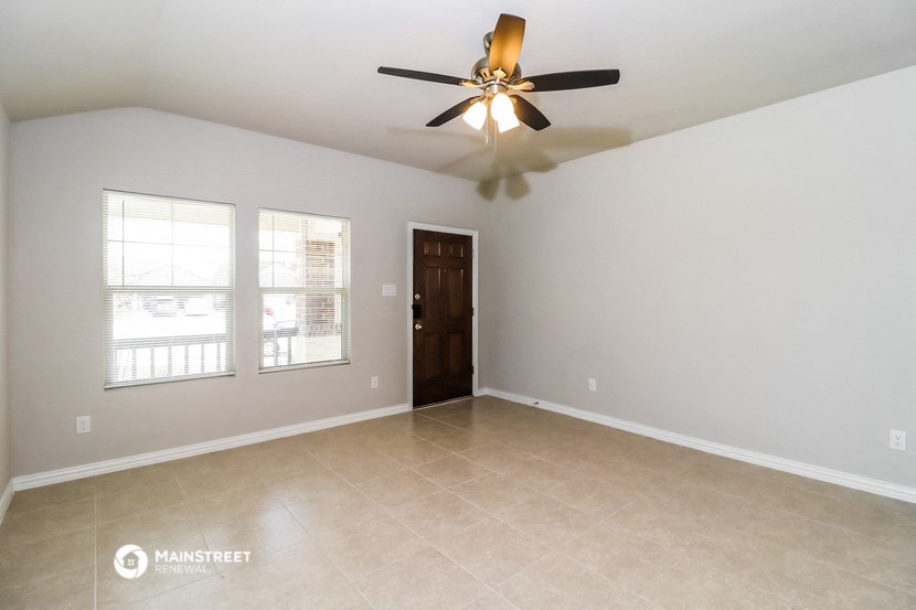 the spacious living room with ceiling fan and tile flooring