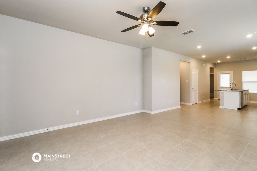 the spacious living room with ceiling fan and tile flooring
