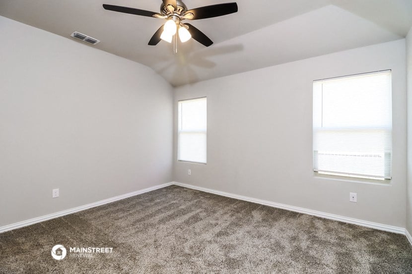 the bedroom with carpet and ceiling fan and two windows
