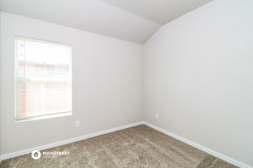 an empty room with a window and carpet