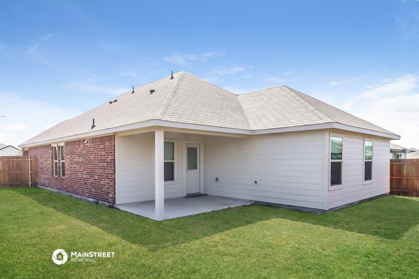 the backyard of a white house with a lawn and a fence