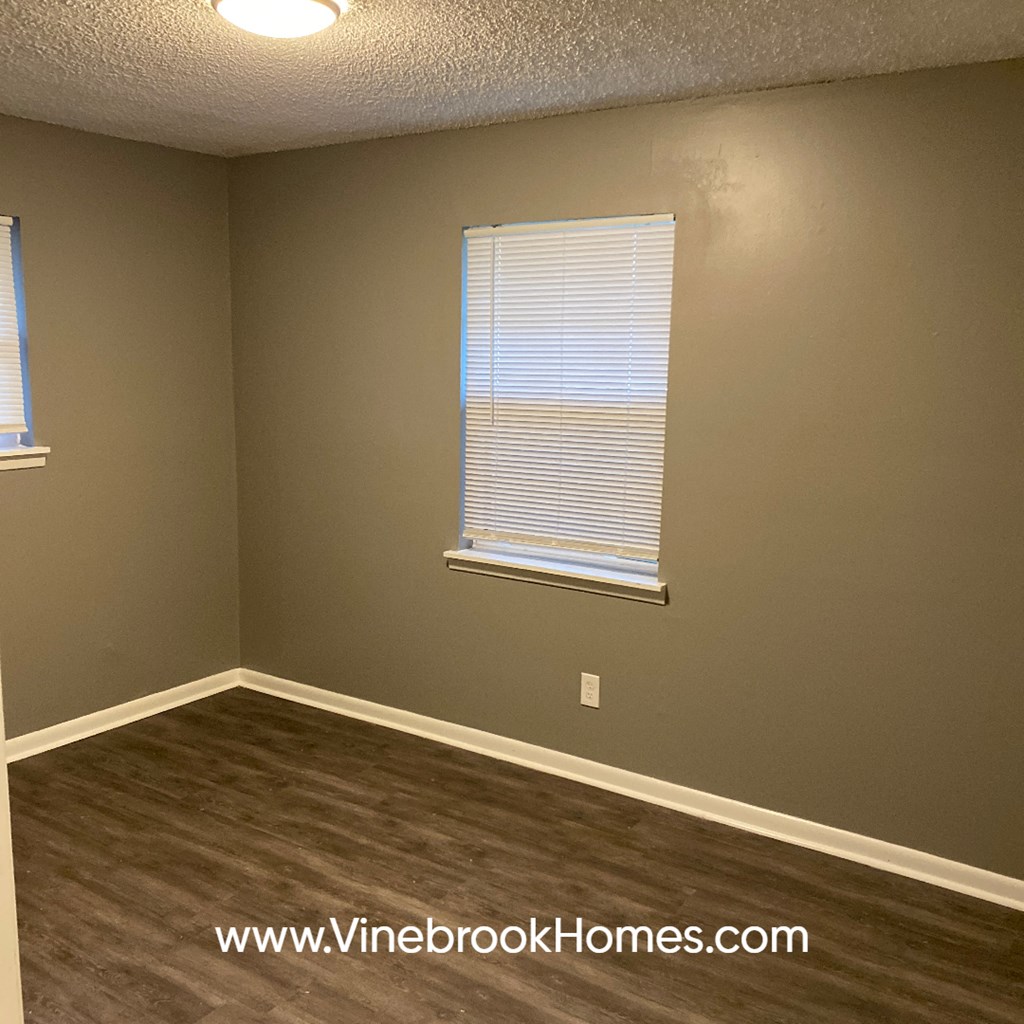 an empty living room with a window and wood floors