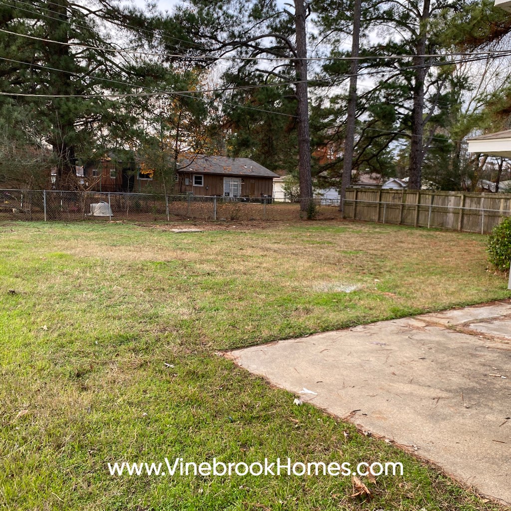 a yard with a fence and a house in the background