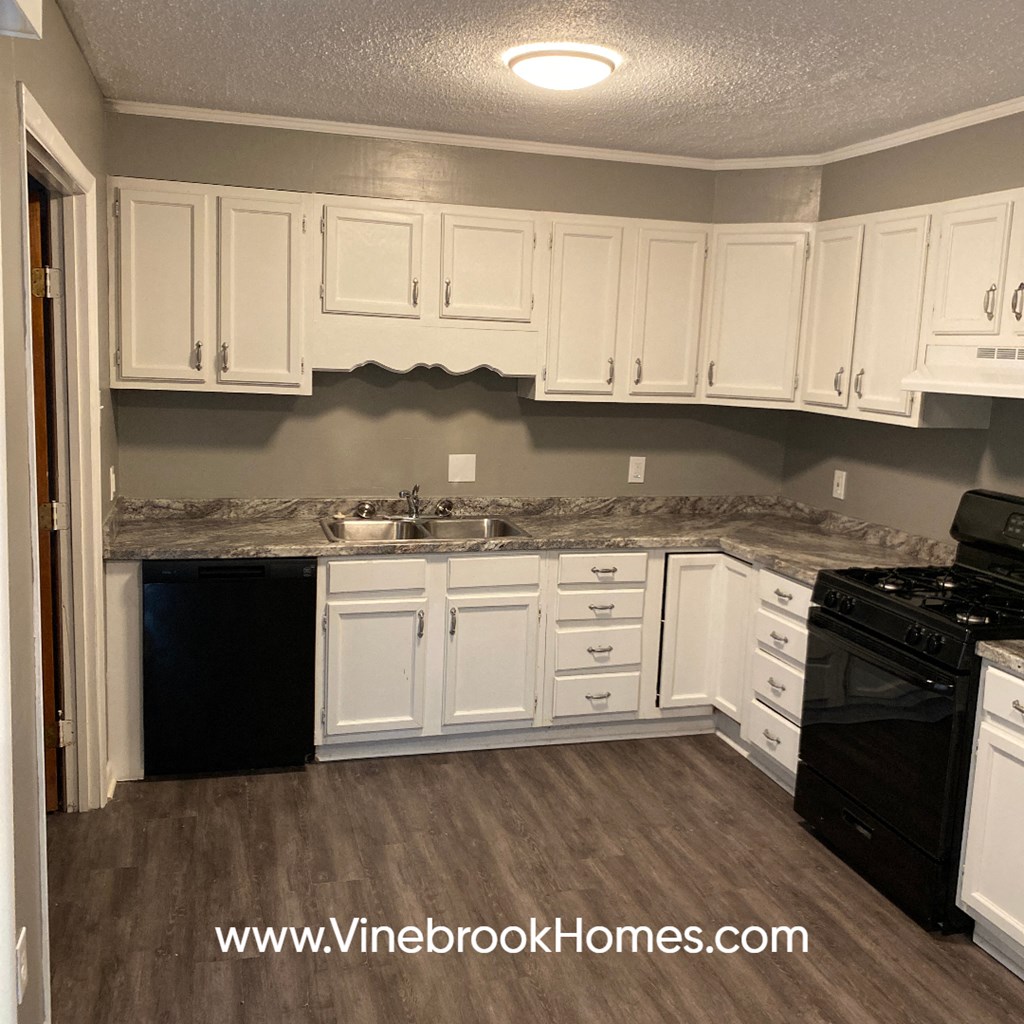 a kitchen with white cabinets and marble counter tops
