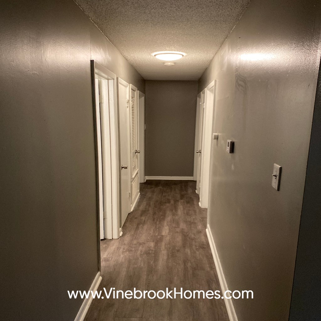 a long hallway with a door to a bedroom and a closet