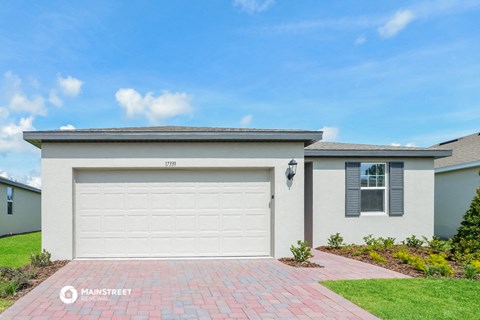 a white house with a garage door and a lawn