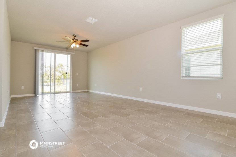 the spacious living room with tile flooring and a ceiling fan