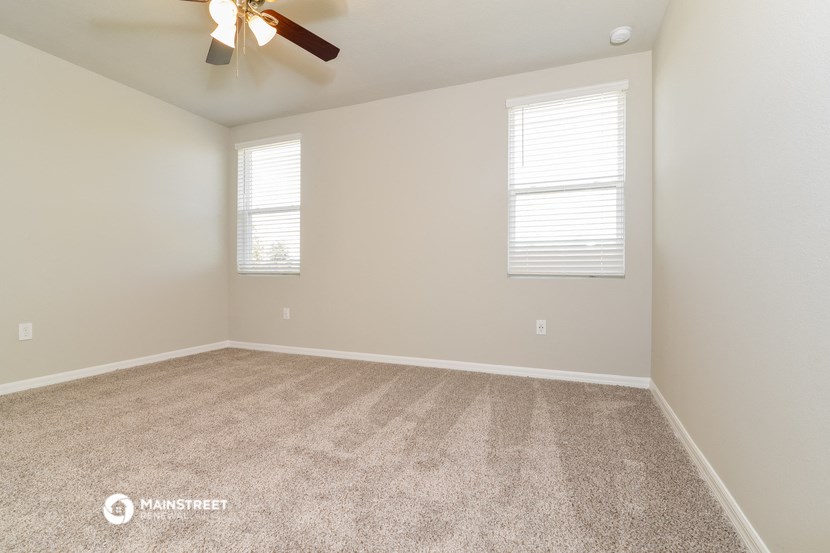 the spacious living room with carpeting and a ceiling fan