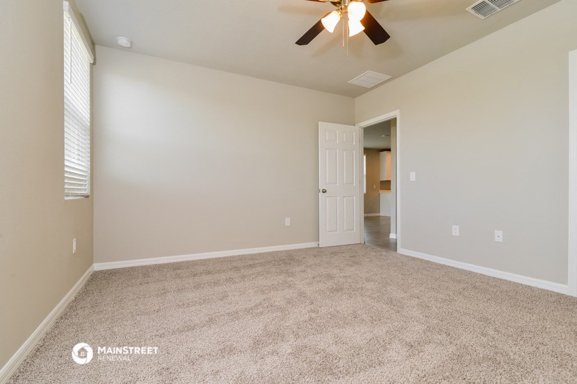 the spacious living room with carpeting and a ceiling fan