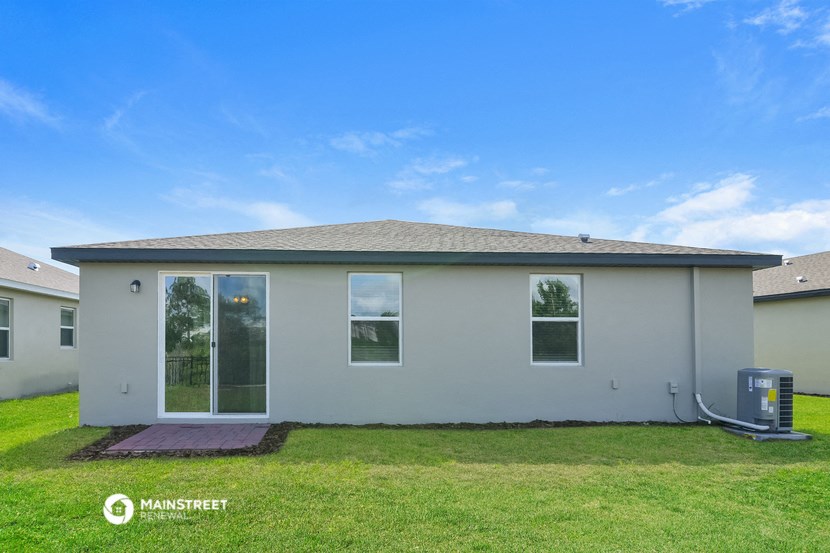 the backyard of a home with a lawn and a blue sky