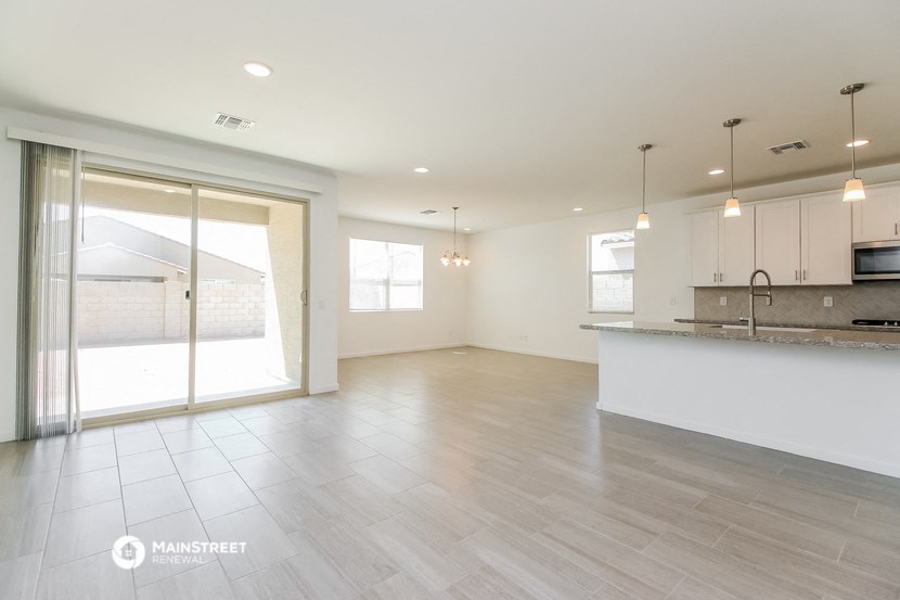 an empty living room with a kitchen and a large window