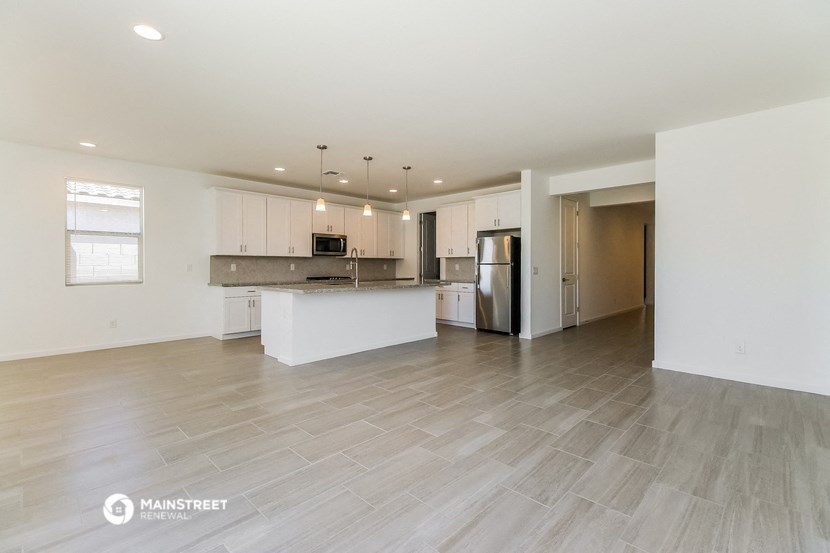 the living room and kitchen of an apartment with white cabinets and a white kitchen island
