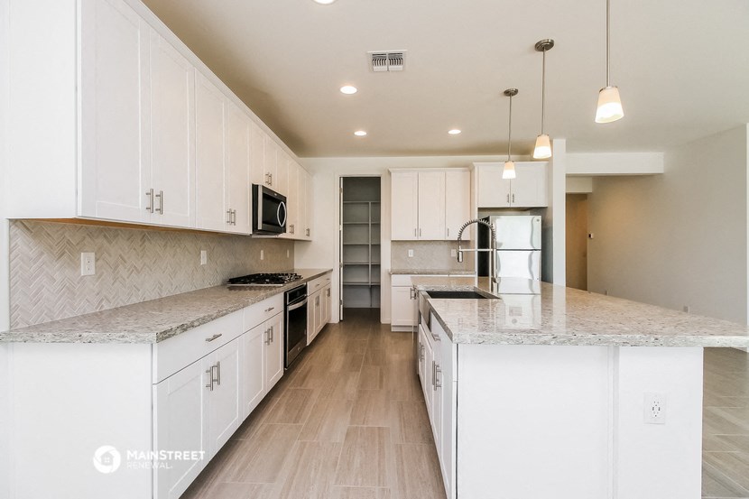 a large kitchen with white cabinets and marble counter tops
