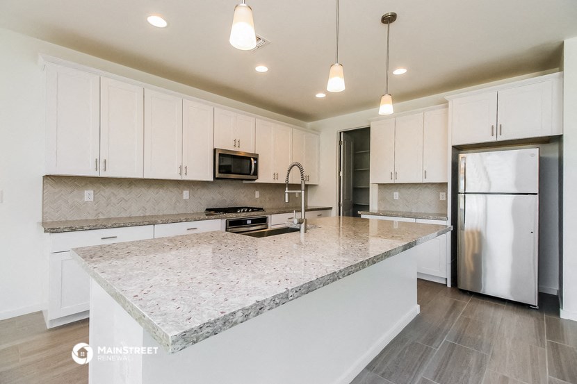a kitchen with white cabinets and a marble counter top