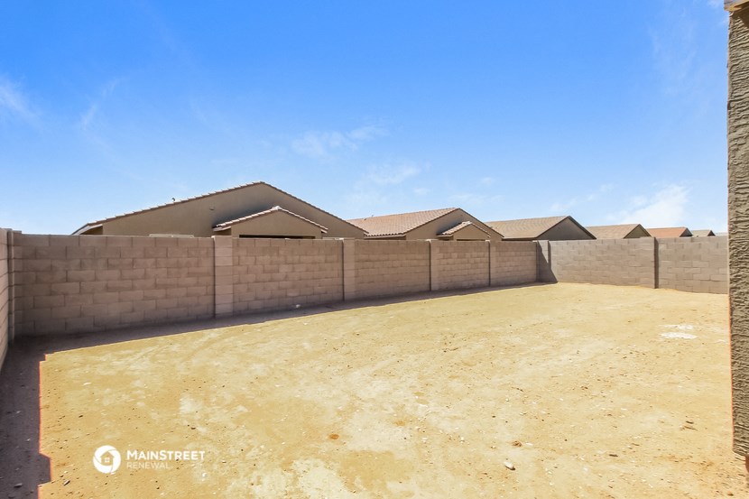 a compound with a fence and some houses in the background