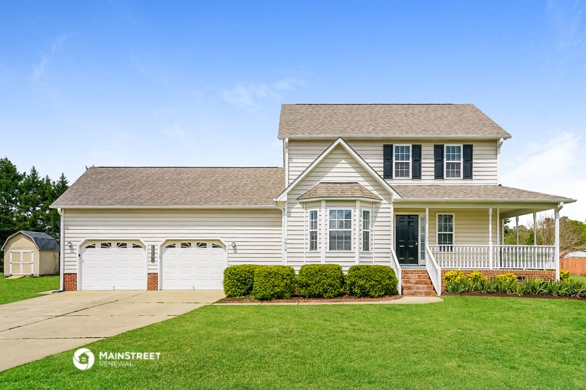 a white house with two garage doors and a lawn