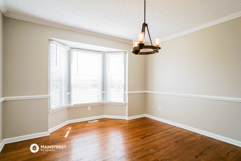 an empty living room with a large window and wood floors