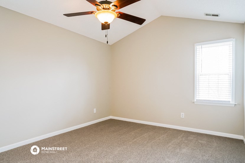 an empty room with a ceiling fan and a window