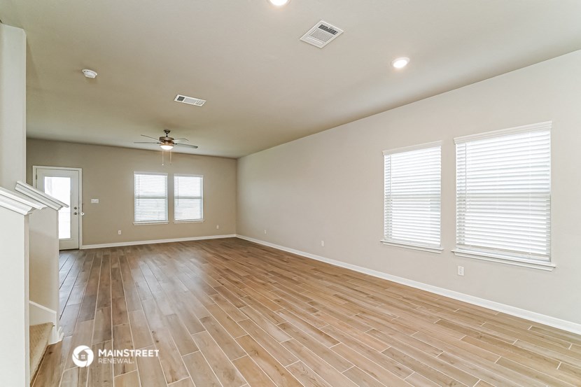 the living room with wood floors and a ceiling fan