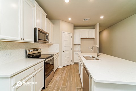 an updated kitchen with white cabinets and stainless steel appliances