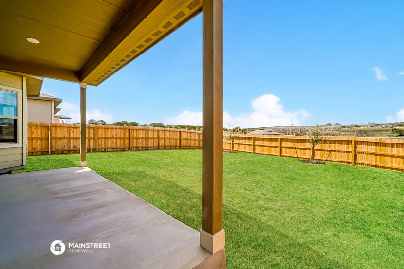 a patio with a lawn and a wooden fence