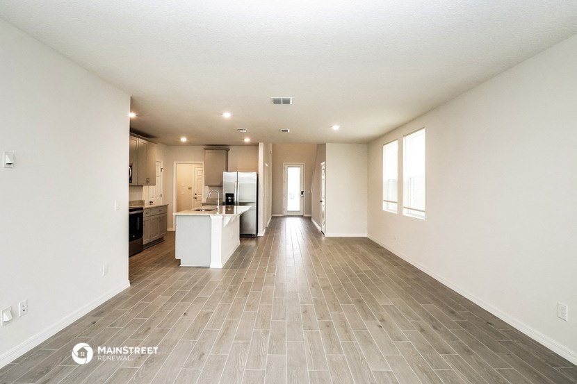 an empty living room and kitchen with white walls and wood flooring