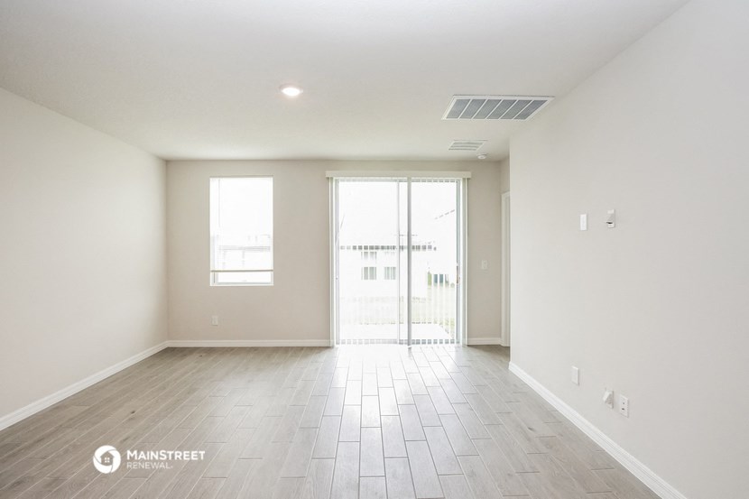 an empty living room with white walls and a sliding glass door