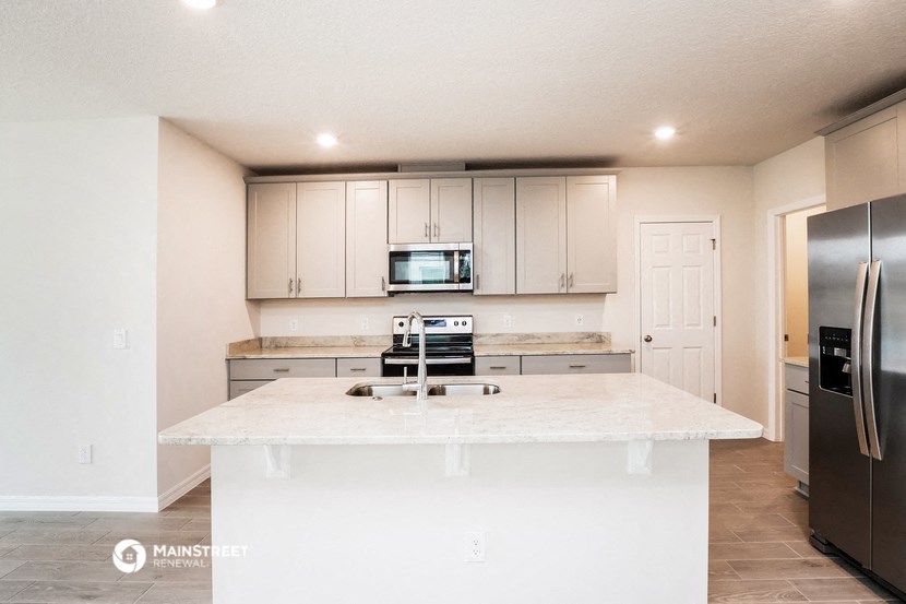 a white kitchen with a large island and stainless steel appliances