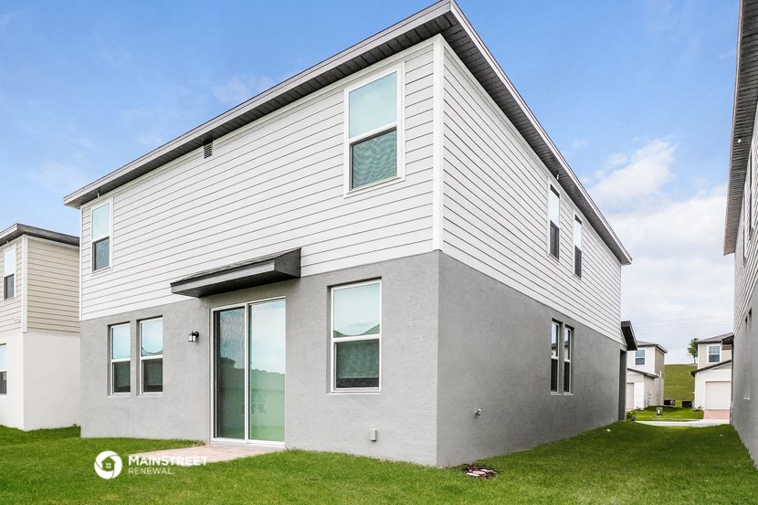 the exterior of a white house with glass doors and a green lawn
