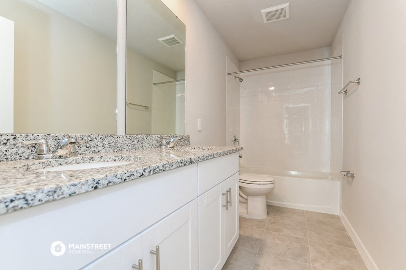 a bathroom with a large mirror and a sink and a toilet