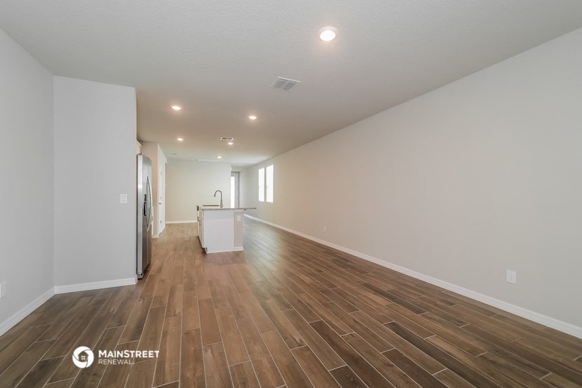 the living room and kitchen are spacious with hardwood floors and white walls