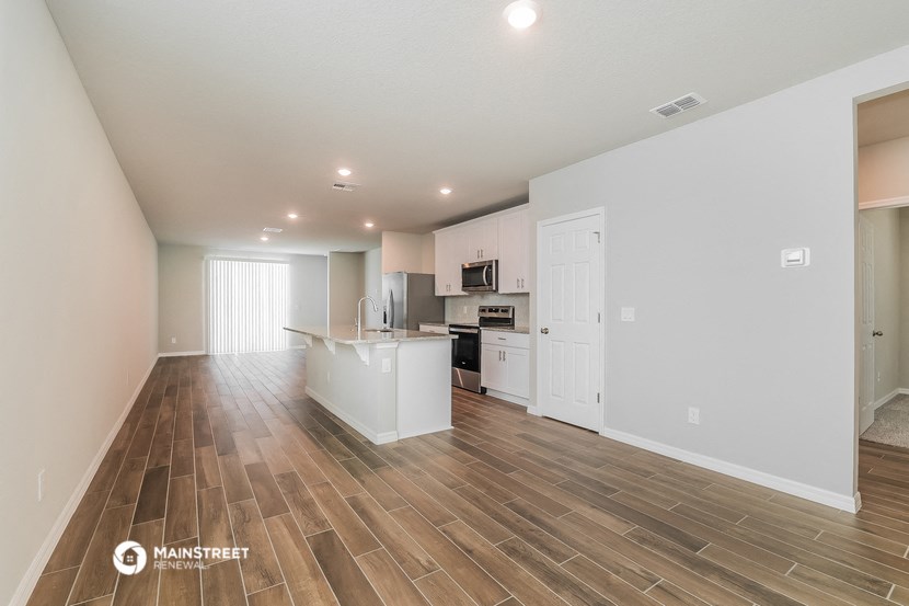 the living room and kitchen of an apartment with wood flooring