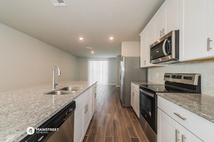 a kitchen with white cabinets and granite counter tops and black appliances